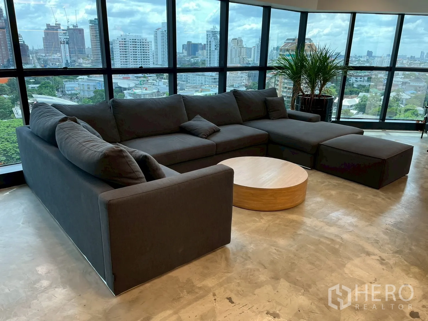 Office Space for rent in Watthana, Bangkok - Lounge corner with large sectional sofa, round coffee table, plants, and panoramic windows.