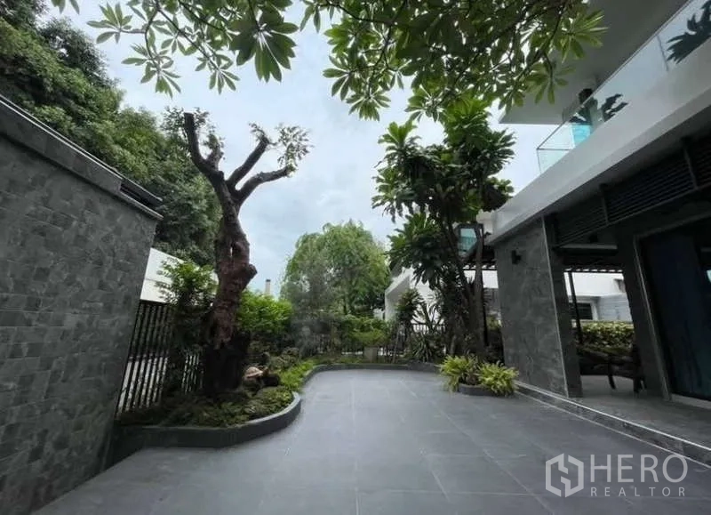 Detached House for sale in Khlong Toei, Bangkok - Wide terrace and garden path surrounded by greenery next to the house.