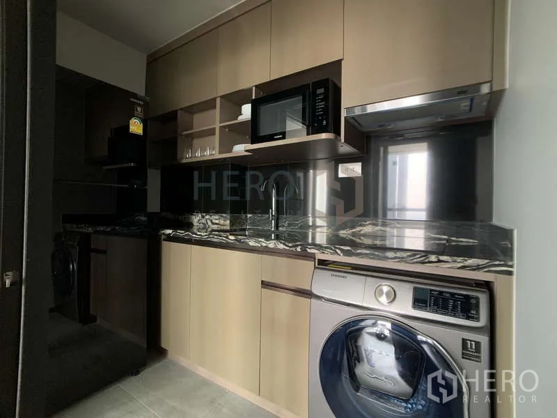 Condominium for rent - Compact kitchen with marble countertop, built-in cabinets, microwave and washer-dryer.