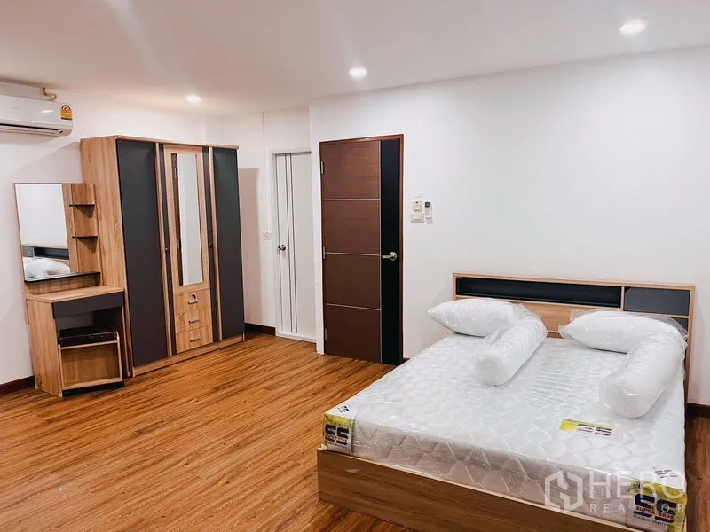 联排别墅 出租在Huai Khwang, Bangkok - 宽敞卧室，木地板、双人床、衣柜与梳妆台。