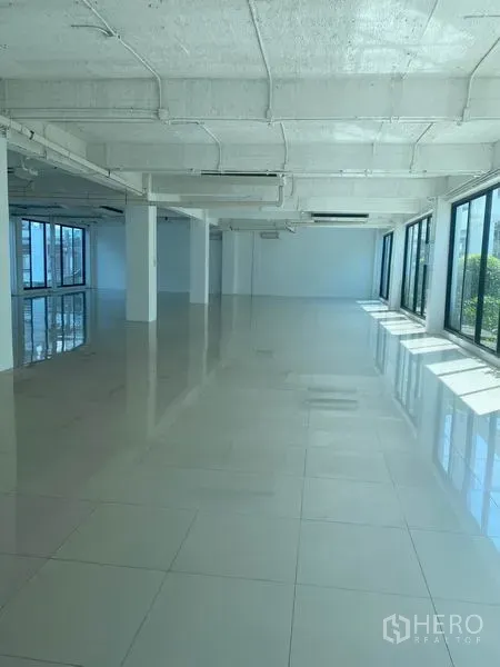 Office Space for rent in Khlong Toei, Bangkok - Spacious open workspace with columns, panoramic windows, tiled floors and exposed ducting.