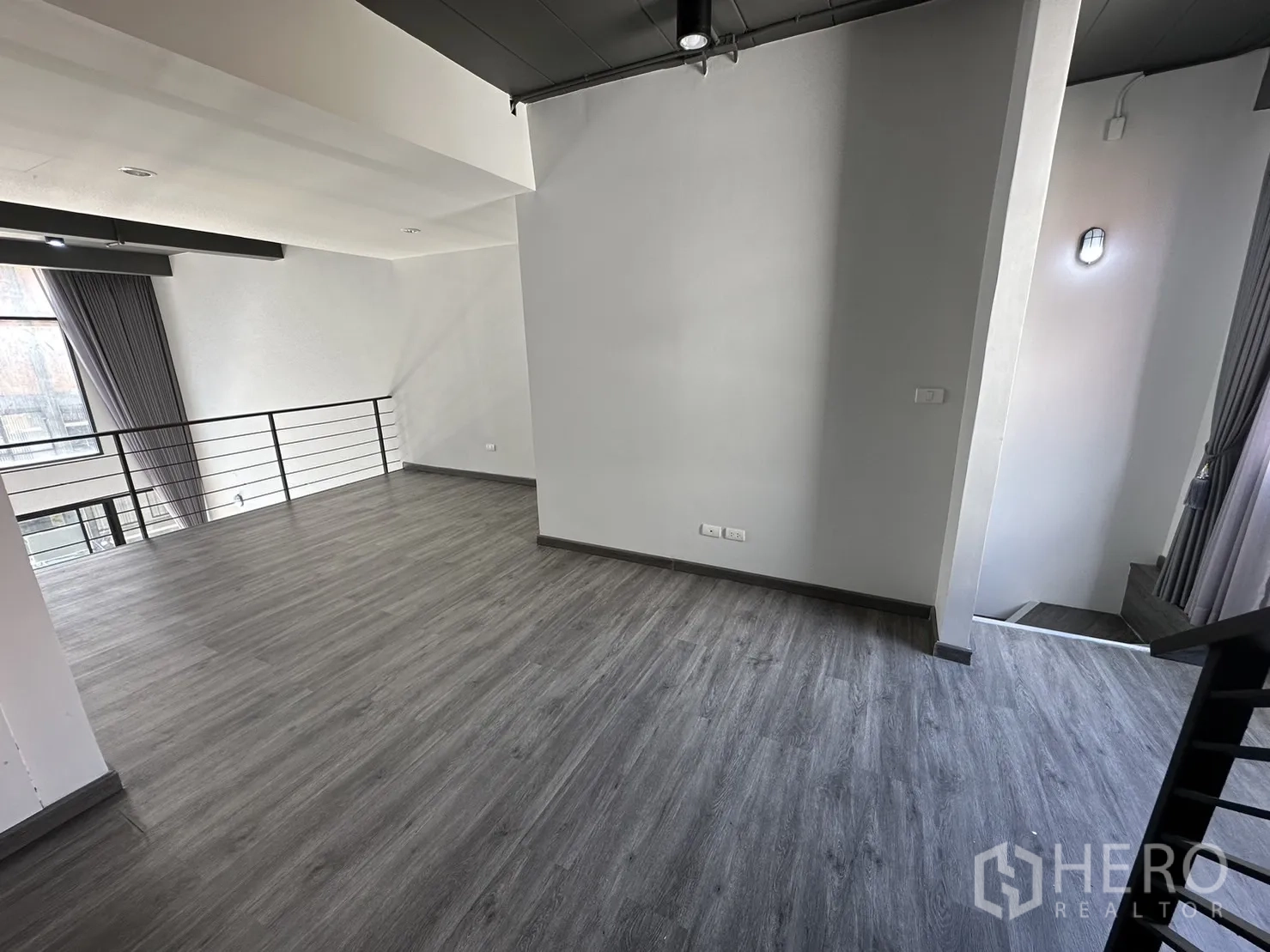 Home Office for rent or sale in Suan Luang, Bangkok - Spacious mezzanine level with grey wood floors, steel railing and a large window.