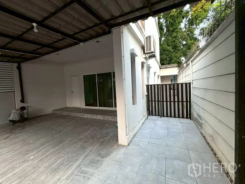 Townhouse for rent in Suan Luang, Bangkok - Ground-floor covered carport and terrace with sliding glass doors.