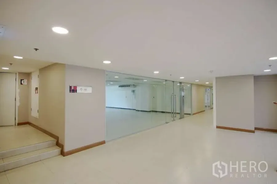 Office Space for rent - Well-lit corridor with glass-walled office entrance and double doors.