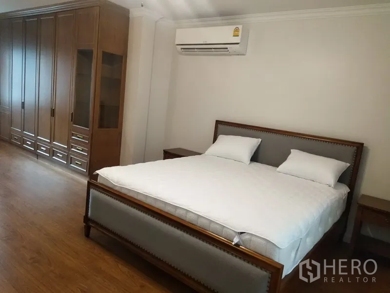 Townhouse for rent in Mueang Samut Prakan, Samut Prakan - Spacious master bedroom with king bed, wall-length wardrobes, and wood floors.