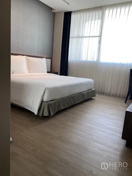 房间 出租在Khlong Toei, Bangkok - 宽敞卧室，配大床、木地板及大窗帘窗户，采光充足。