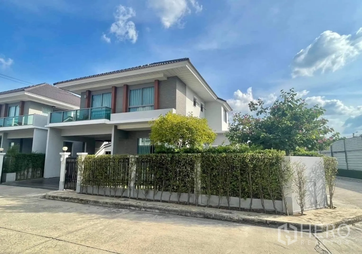 Detached House for rent in Bang Phli, Samut Prakan - Modern detached house exterior on a corner lot with hedge fence and a covered carport.
