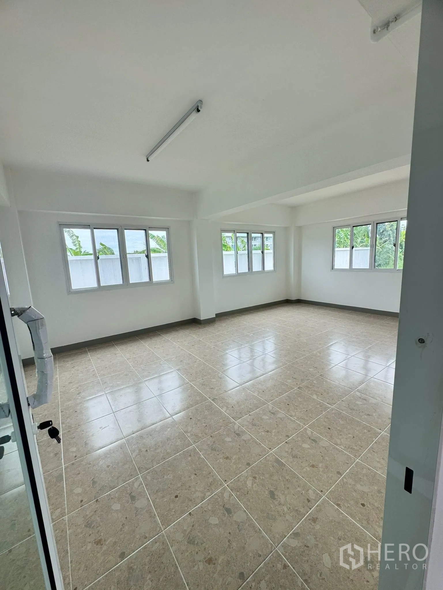 Warehouse for rent in Bang Bo, Samut Prakan - Bright corner upstairs office with windows on two sides and a tiled floor.