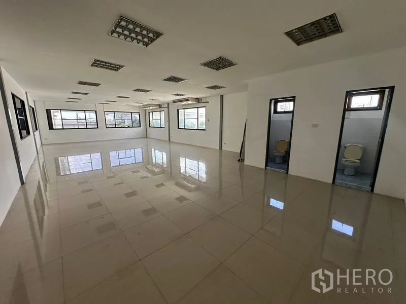 Warehouse for rent in Suan Luang, Bangkok - Open office floor with two restrooms and reflective tile flooring.