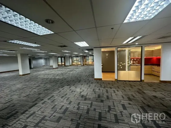 Office Space for rent in Khlong Toei, Bangkok - Spacious office floor with carpet tiles and a glass-fronted room with red accent cabinetry.