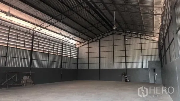 Warehouse for rent in Bang Bon, Bangkok - Spacious warehouse interior with high steel trusses, vented panels and concrete floor.