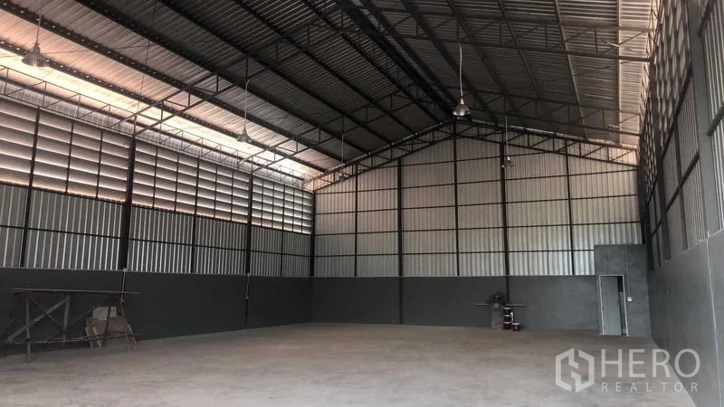 Warehouse for rent in Bang Bon, Bangkok - Spacious warehouse interior with high steel trusses, vented panels and concrete floor.