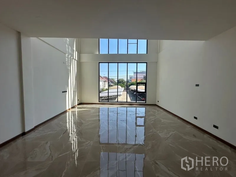 Home Office for rent in Wang Thonglang, Bangkok - Spacious living zone with floor-to-ceiling windows and high ceiling filling the room with light.