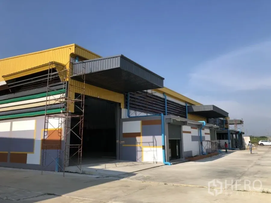 Factory for rent in Khlong Luang, Pathum Thani - Row of modern factory warehouses with wide concrete driveway and loading canopies.
