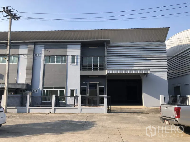 Factory for rent in Lam Luk Ka, Pathum Thani - Modern factory facade with two‑storey office, balcony and large roller shutter in a secured Lam Luk Ka compound.