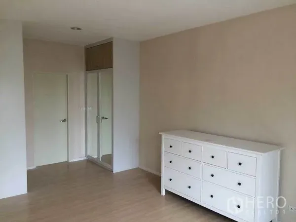 Townhouse for sale in Suan Luang, Bangkok - Spacious bedroom with white dresser and mirrored built-in wardrobe.