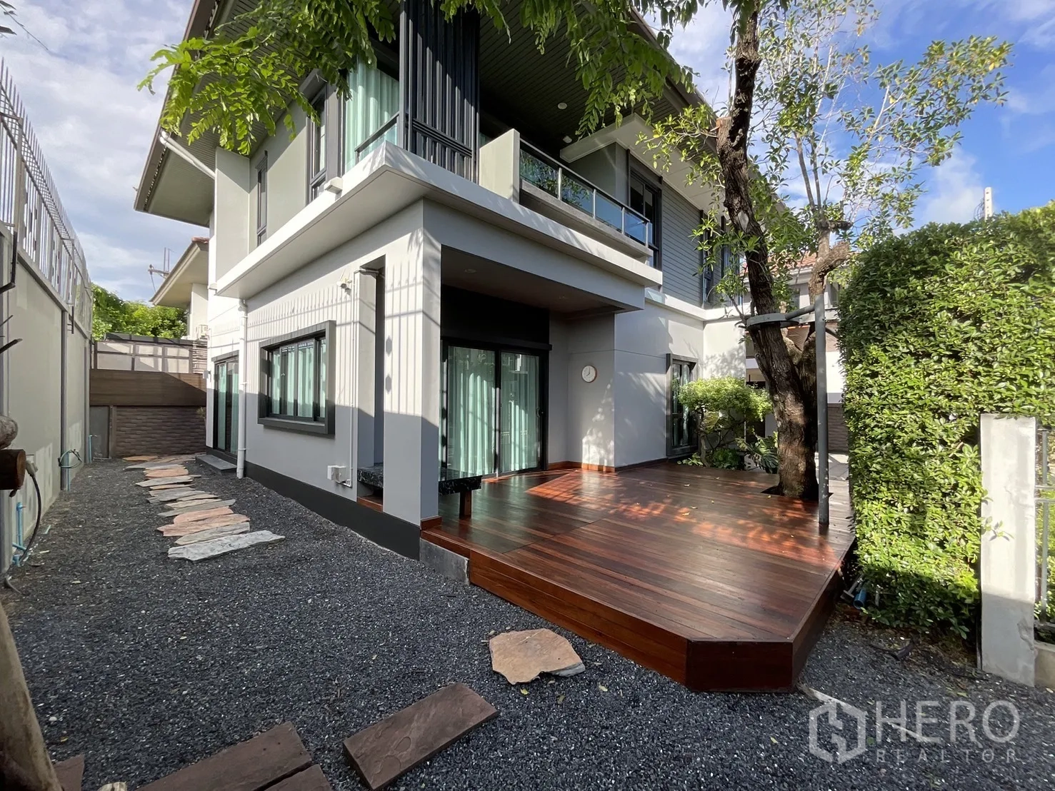 Detached House for rent or sale in Lam Luk Ka, Pathum Thani - Side exterior showing large timber deck, sliding glass doors and gravel garden walkway.
