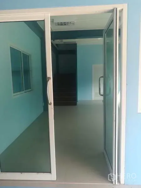 Factory for sale in Sai Noi, Nonthaburi - Glass sliding door entry leading into the office area with a staircase beyond.