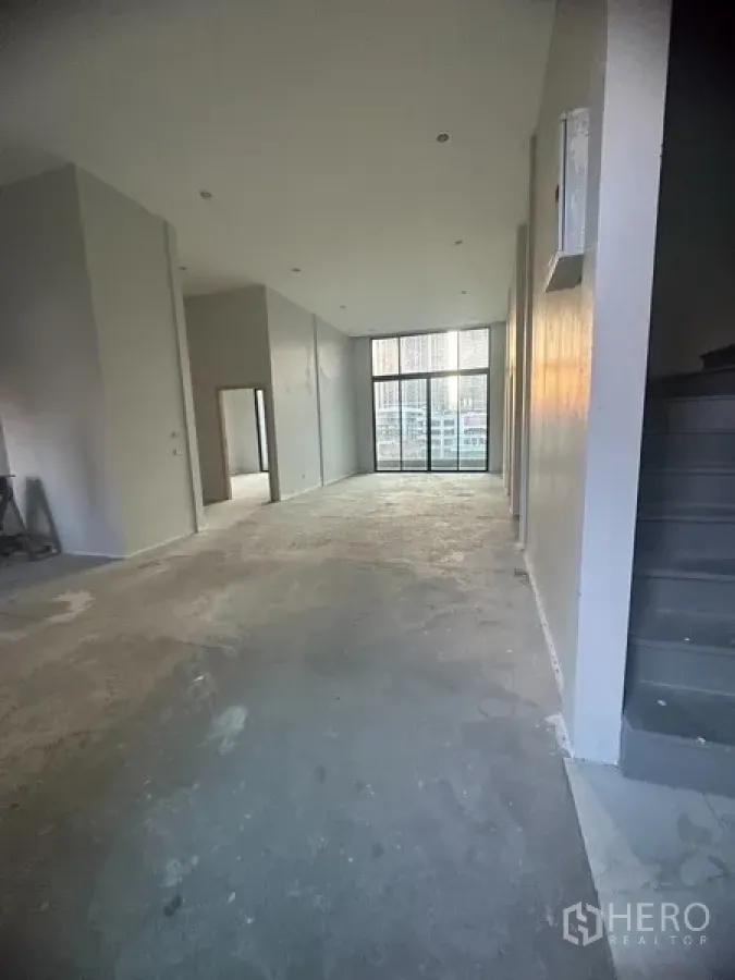 Shophouse for rent in Watthana, Bangkok - Open-plan shophouse interior with double-height ceiling and full-height glass frontage in Ekkamai.
