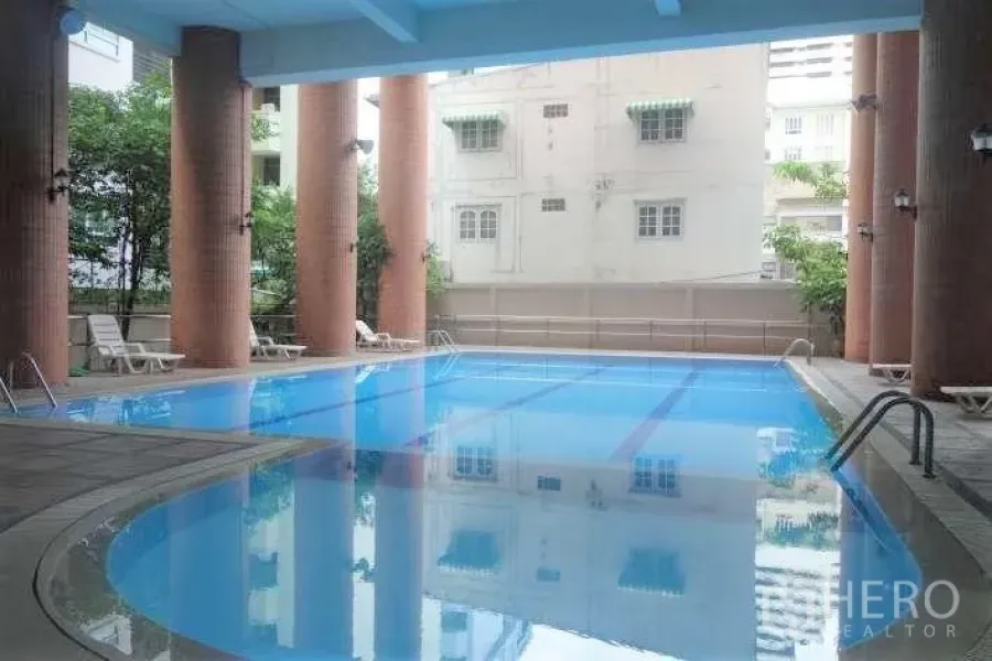 Condominium for rent in Watthana, Bangkok - Covered condominium swimming pool with tall columns and lounge chairs in Watthana, Bangkok.