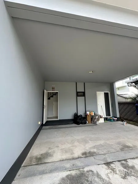 Detached House for rent in Lam Luk Ka, Pathum Thani - Covered carport area with concrete floor and side storage doors.