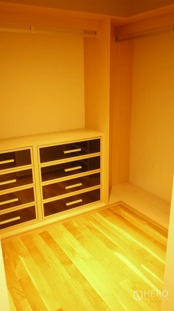 Condominium for rent in Khlong Toei, Bangkok - Walk-in closet with built-in drawers, hanging rails and wooden flooring.