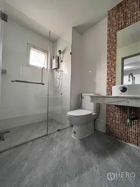 Townhouse for rent in Khlong Toei, Bangkok - Modern bathroom with glass-enclosed shower, water heater and mosaic-tile vanity wall.