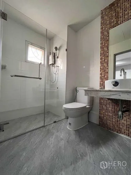 Townhouse for rent in Khlong Toei, Bangkok - Modern bathroom with glass-enclosed shower, water heater and mosaic-tile vanity wall.
