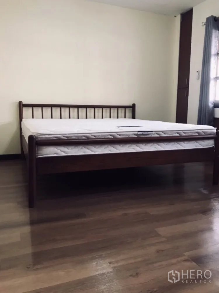 Townhouse for rent in Watthana, Bangkok - Bedroom with wooden bed frame and mattress over polished wood flooring.
