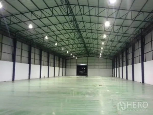 Warehouse for rent in Chon Buri - Spacious column-free warehouse interior with high steel truss roof, bright LED lights, and epoxy floor.
