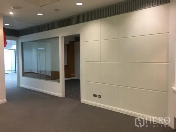 Office Space for rent in Chatuchak, Bangkok - Hallway with white paneled walls, large interior window, and recessed lighting.