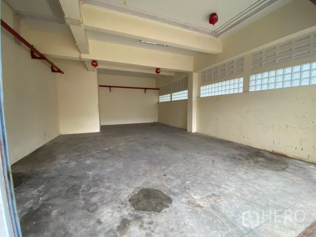 Factory for rent in Khlong Toei, Bangkok - Small storage or workshop room with sprinklers and glass block windows.