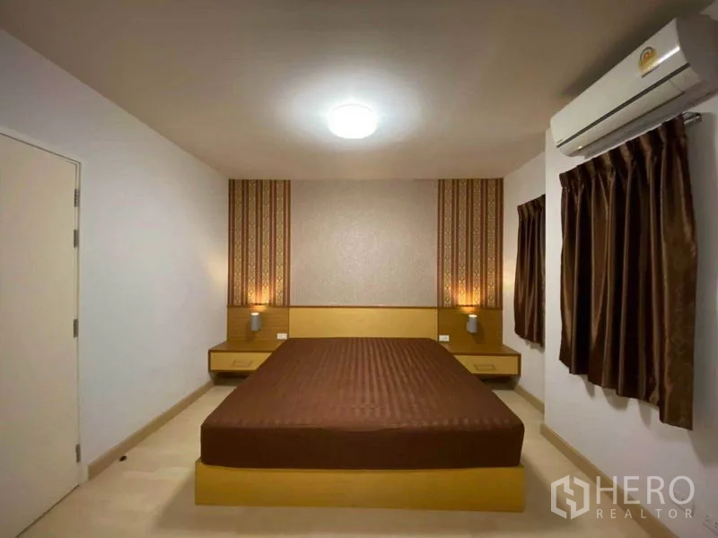 Townhouse for rent in Suan Luang, Bangkok - Master bedroom with large bed, bedside tables, feature wallpaper and two windows.