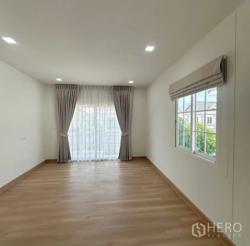 Detached House for rent in Mueang Samut Prakan, Samut Prakan - Large room with sliding glass doors, sheer curtains and a bright corner window.