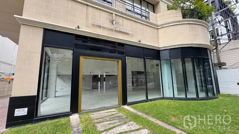 Retail Space for rent in Watthana, Bangkok - Street-facing shopfront with gold-trimmed glass entrance and grass path.