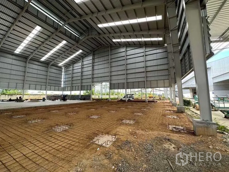 Warehouse for rent in Wang Noi, Phra Nakhon Si Ayutthaya - High-roof warehouse interior under construction with skylights and rebar floor grid.