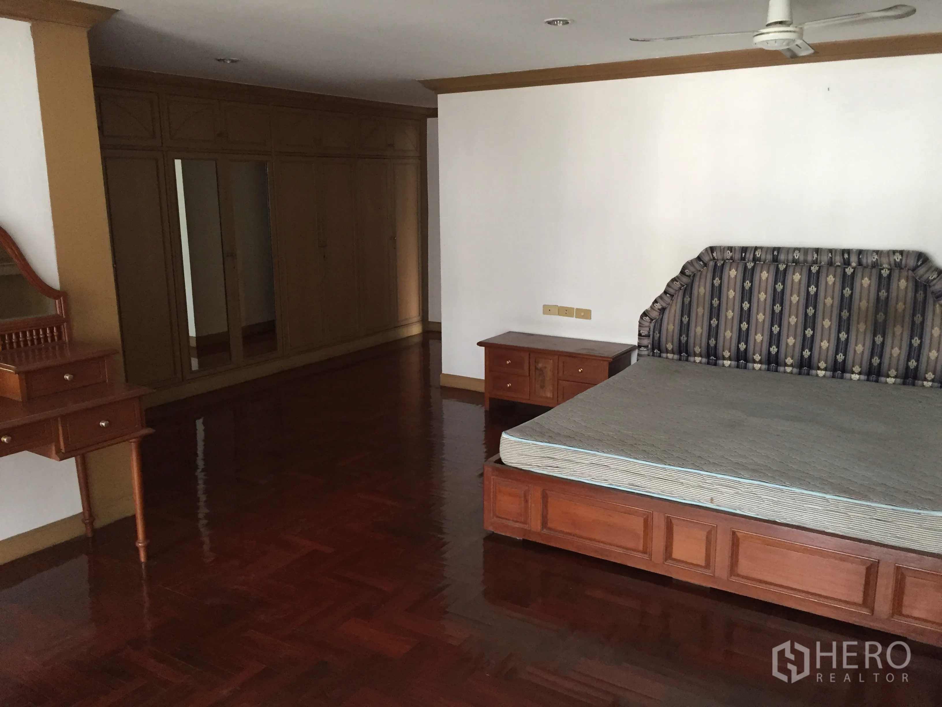 Condominium for rent in Khlong Toei, Bangkok - Bedroom featuring wall-length wardrobes, dressing table, and shiny parquet flooring.