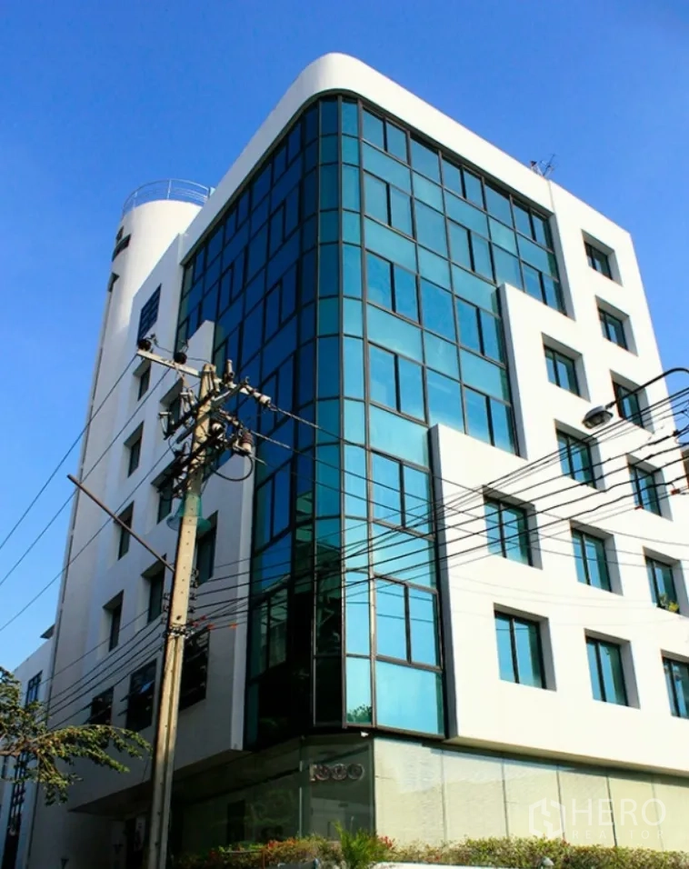 办公室 for rent in Suan Luang, Bangkok - 现代多层办公楼，蓝色玻璃幕墙与白色外立面，晴天拍摄