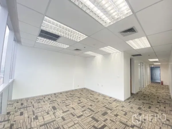 Office Space for rent in Chatuchak, Bangkok - Open-plan workspace with large windows, grid ceiling lights, and patterned carpet.