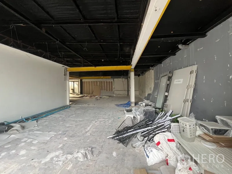 Retail Space for rent in Watthana, Bangkok - Open-plan retail interior under renovation with black ceiling, yellow beams and concrete floor.
