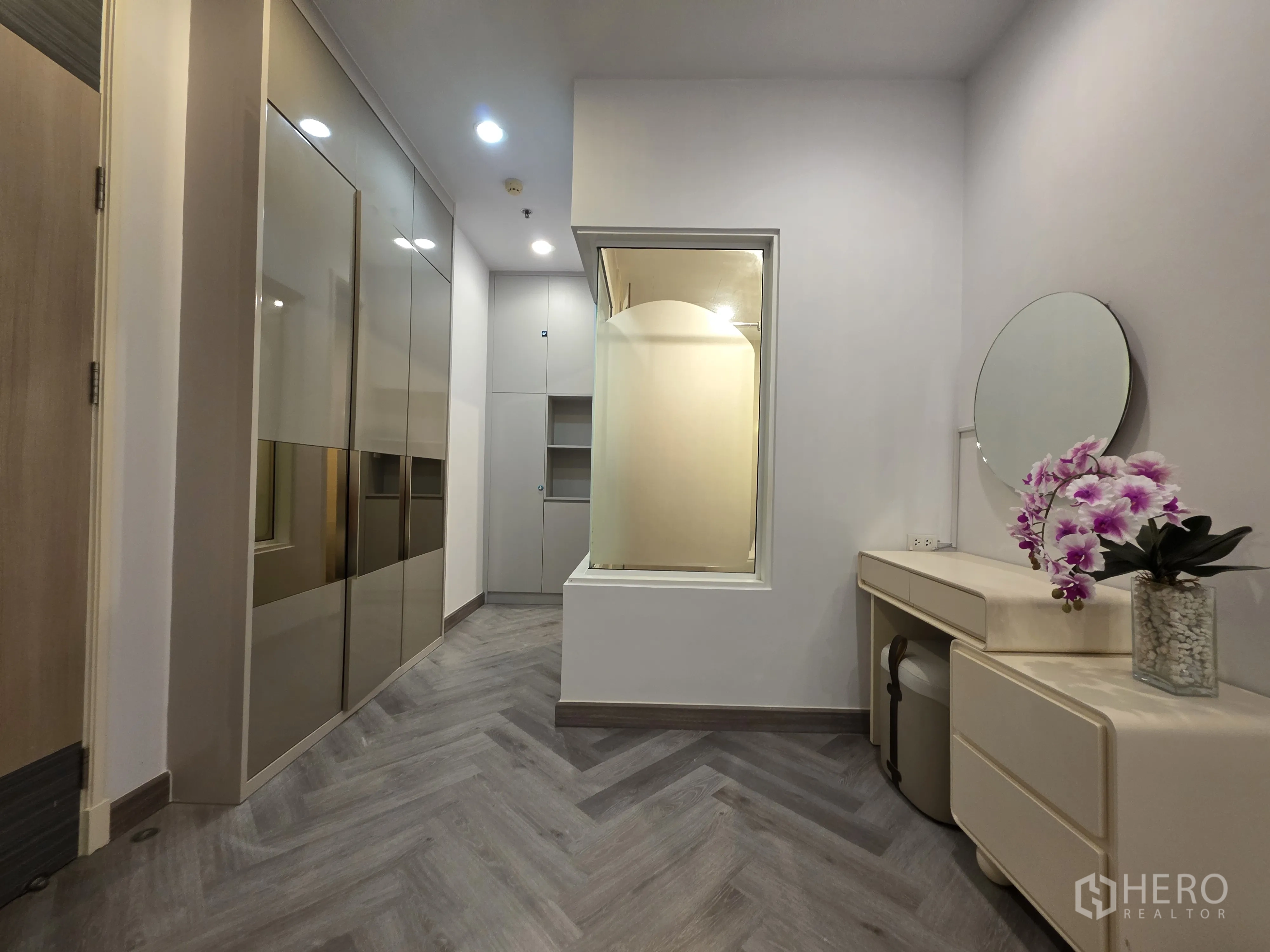 Condominium for rent in Bang Kapi, Bangkok - Hallway with glossy wardrobes and a dressing table beside an interior window.