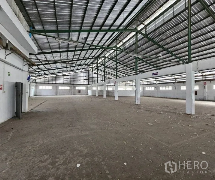 Factory for rent in Bang Kho Laem, Bangkok - High-ceiling shed with green truss beams and bright perimeter windows.