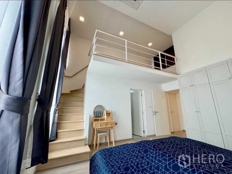 Townhouse for rent or sale in Prawet, Bangkok - Bedroom with staircase to a loft, built‑in wardrobe and dressing table.