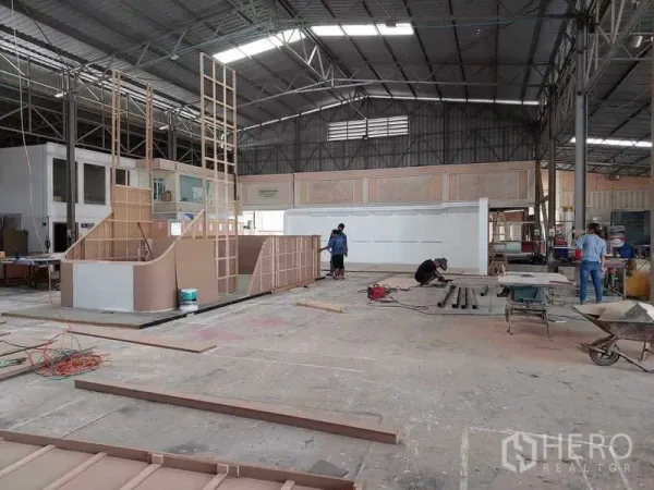 Warehouse for sale in Lam Luk Ka, Pathum Thani - Open-plan factory hall with tall roof, natural light and construction of interior partitions on the production floor.