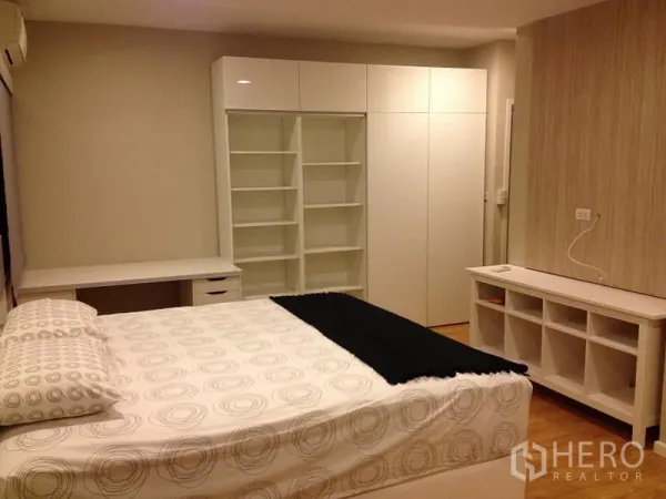 Condominium for rent in Pathum Wan, Bangkok - Master bedroom angle with built-in shelving, work desk and wardrobe in white.