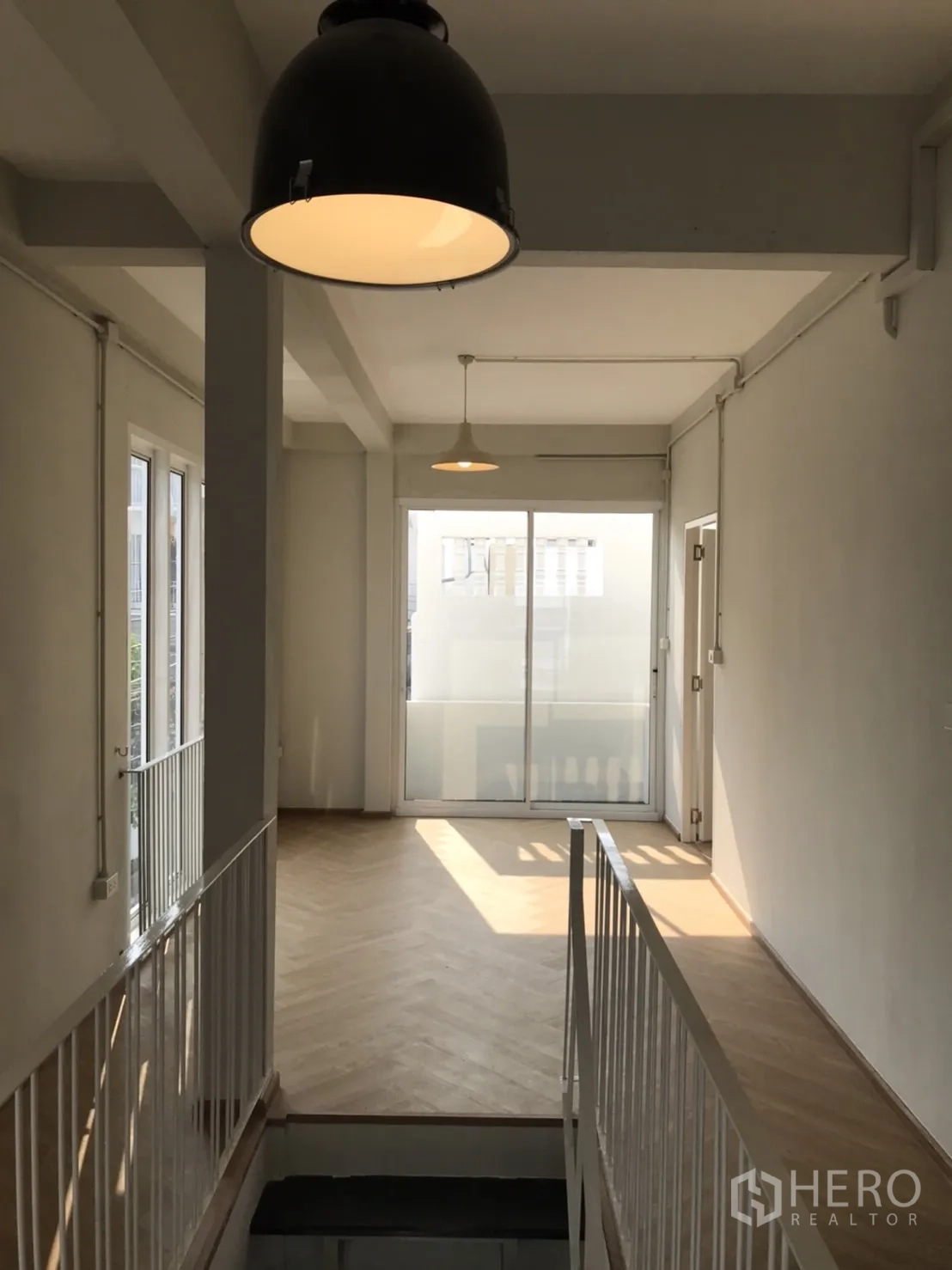 Detached House for rent or sale in Din Daeng, Bangkok - Bright upstairs landing with pendant lights, herringbone wood floor and sliding glass doors.