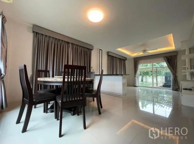 Detached House for sale in Bang Phli, Samut Prakan - Dining area with round table beside wide curtained windows, connected to the kitchen.