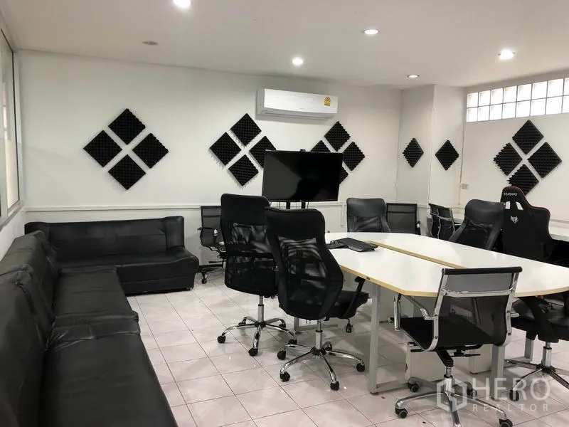 Warehouse for rent in Chatuchak, Bangkok - Conference room with TV, black sofas, meeting tables and wall acoustic panels.