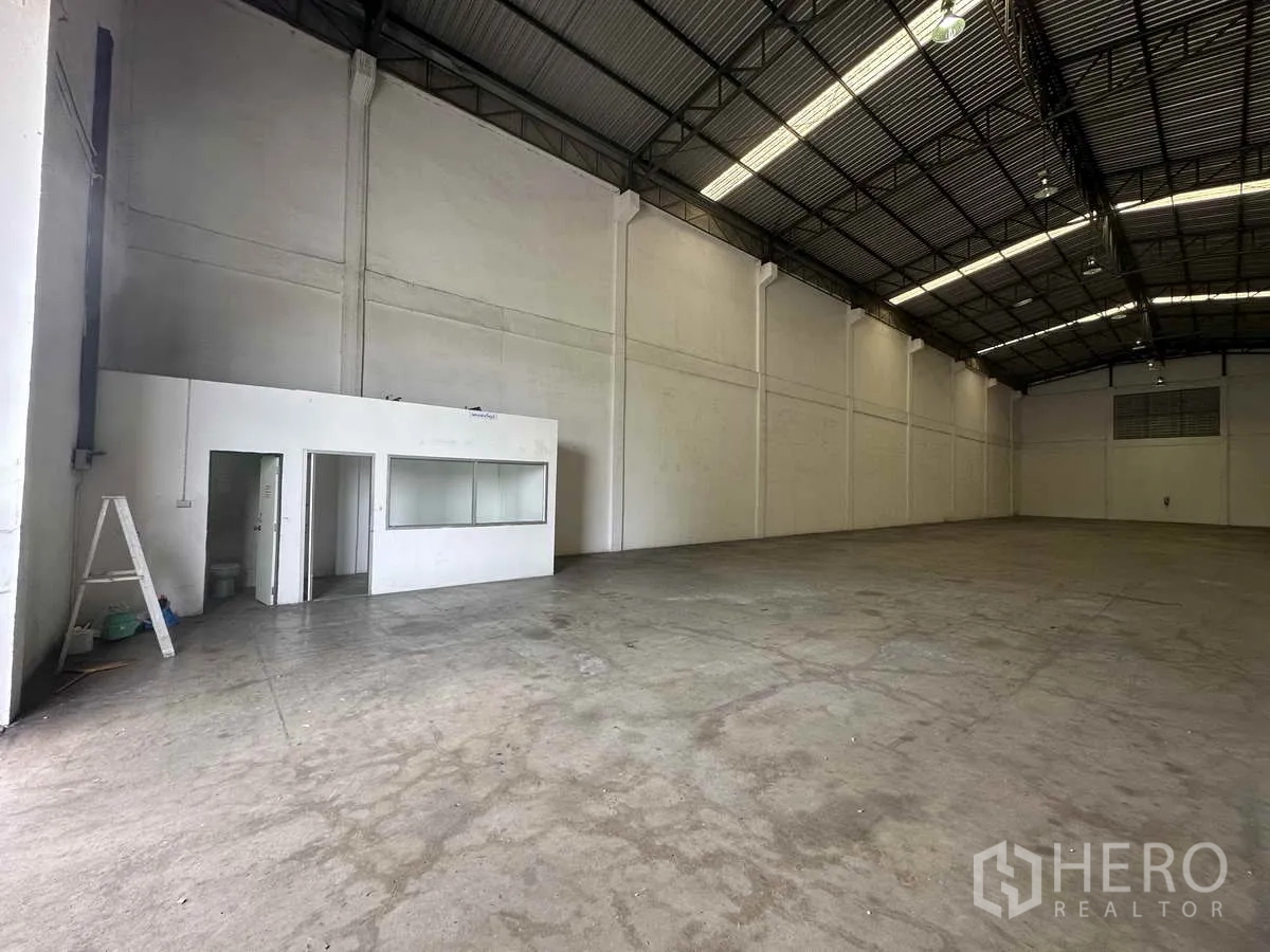 Warehouse for rent in Bang Pa-in, Phra Nakhon Si Ayutthaya - Corner interior view showing the built-in office room and expansive warehouse floor space.