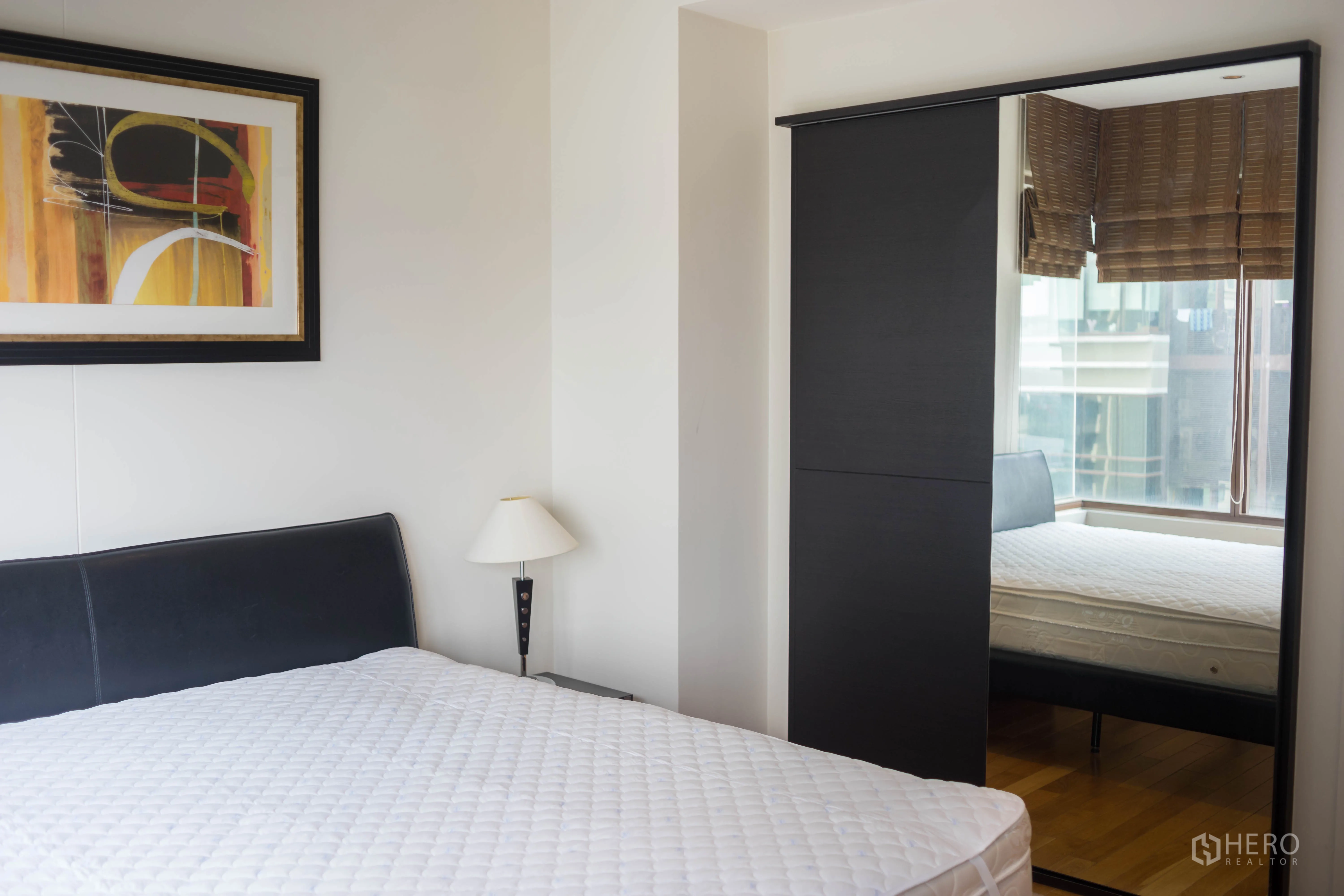 Condominium for rent or sale in Khlong Toei, Bangkok - Bright bedroom with double bed, artwork and a mirrored sliding wardrobe.